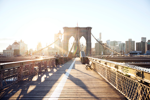People walking and jogging along a footpath on the Brooklyn Bridge on a sunny day in winter