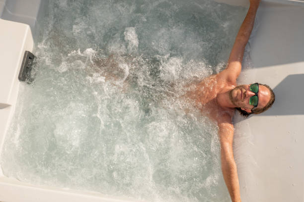 Young man enjoys a spa bath outdoors stock photo