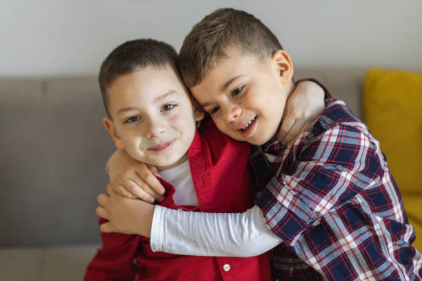 Brothers enjoying at home. Boys hugging. Little boys playing at home. Cute boys spending time together. Two kids lying at couch. Two cute brothers hugging. Cute brothers posing for the camera.