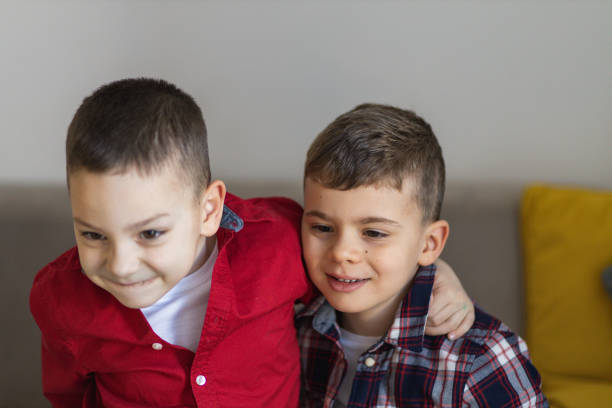 Brothers enjoying at home. Boys hugging. Little boys playing at home. Cute boys spending time together. Two kids lying at couch. Two cute brothers hugging.