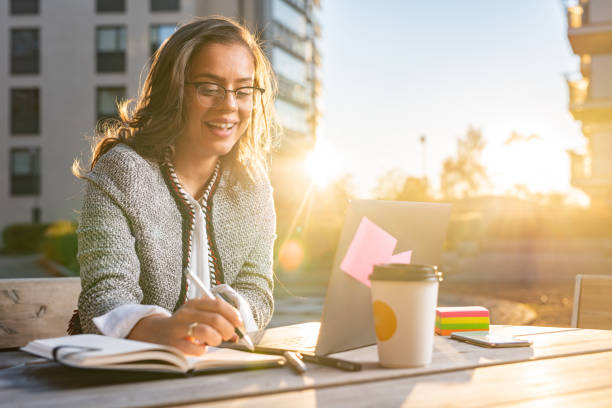 istock Happy woman taking notes while working outdoors 1392296877