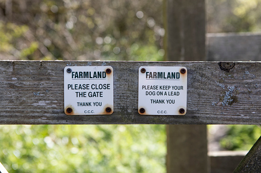 Sign on a gate advising walkers to close the gate and to keep dogs on a lead