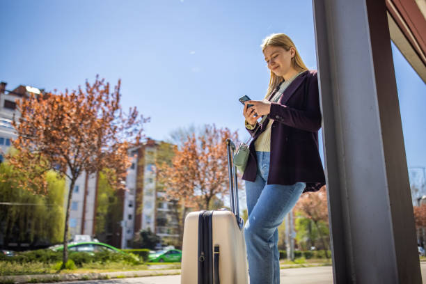 istock Female traveler using mobile phone while waiting for a taxi 1392298815