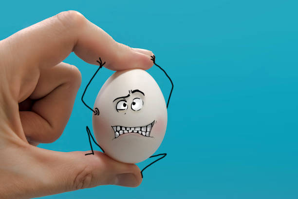 the hand squeezes a white egg in its fingers, which resists, grimacing. On a blue background. There is a place for your text. big frame