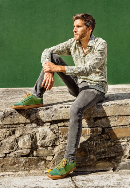 istock Young man sitting outside by a green wall 1392301062