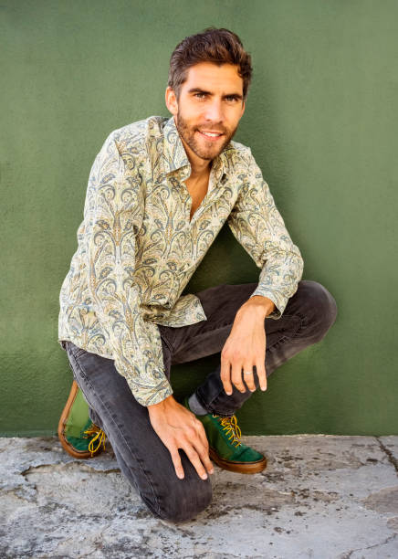 istock Handsome young man sitting by a green wall outside 1392301065