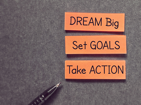 Motivational inspirational quote dream big set goals take action text written on notepaper background.