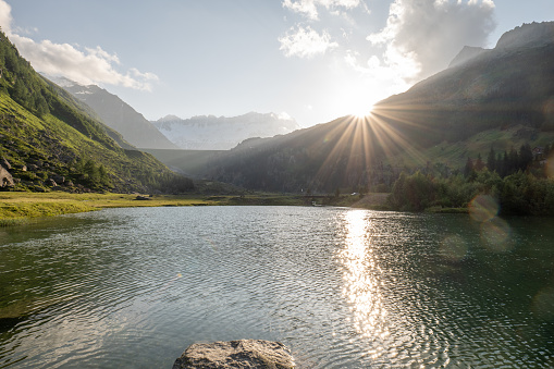 Sun rising from the valley on a summer day, calm water lake and clear sky.
