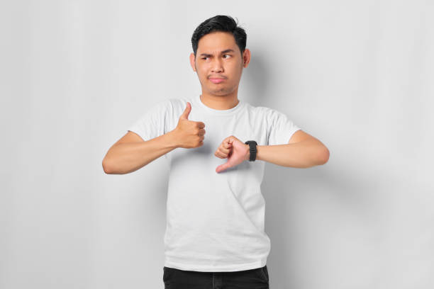 istock Young Asian man showing thumbs up and down decision isolated on white background 1392304237