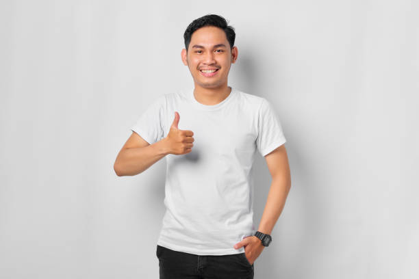istock Smiling young Asian man showing thumbs up gesture, Approving expression looking at the camera isolated on white background 1392304240