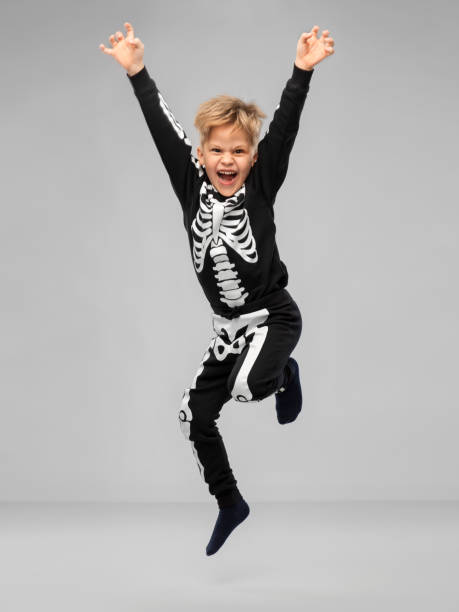 happy boy in halloween costume of skeleton jumping stock photo
