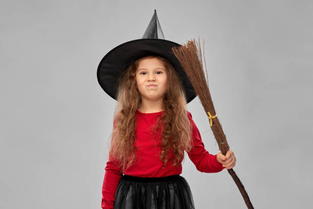 istock girl in black witch hat with broom on halloween 1392308192