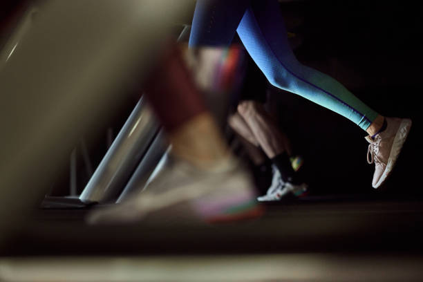 Unrecognizable athletic woman exercising on treadmill in a health club. Copy space.
