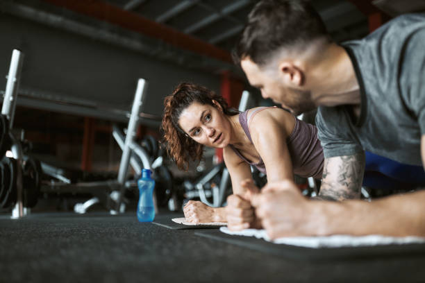 istock Athletic couple talking in plank position in a gym. 1392309224