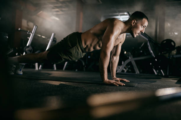 muscular build men exercising push-ups in a gym. - exercising men push ups muscular build imagens e fotografias de stock