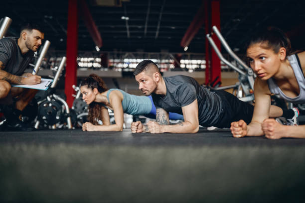 istock Athletic people exercising in plank position on sports training with their coach. 1392309806