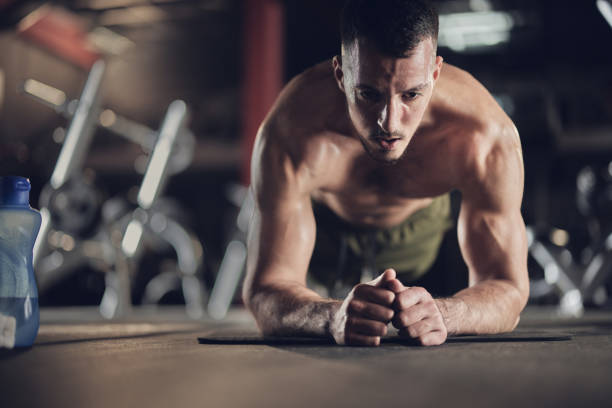 istock Muscular build men exercising endurance in plank position in a gym. 1392309865