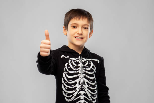 istock boy in halloween skeleton costume shows thumbs up 1392310157