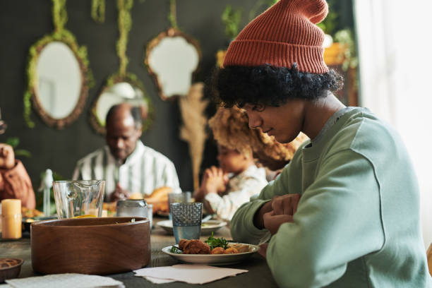 istock Boy praying with family at dinner 1392311617