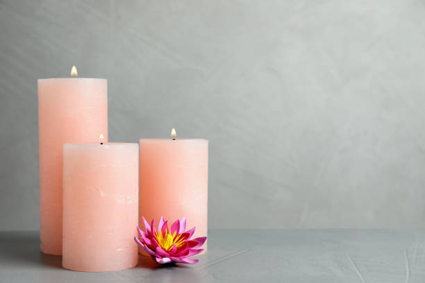 istock Burning candles and lotus flower on light grey stone table. Space for text 1392312814