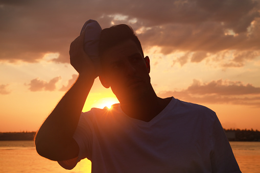 Man with cold pack suffering from heat stroke outdoors at sunset