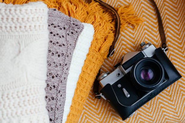 istock Stack of soft warm plaids and retro camera, top view. 1392315335