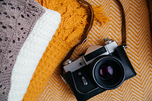 Stack of soft warm plaids and retro camera, top view. Autumn-winter concept of cozy in the home. Background
