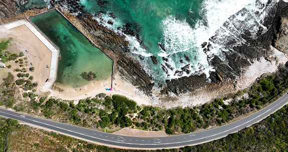 Aerial view over a scenic coastline and biosphere near Cape Town. A small tidal pool lies on the coastline