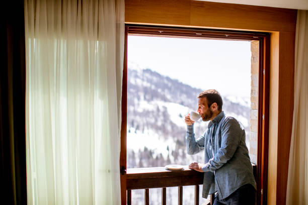 istock Young man with cup of hot tea at winter window 1392317508