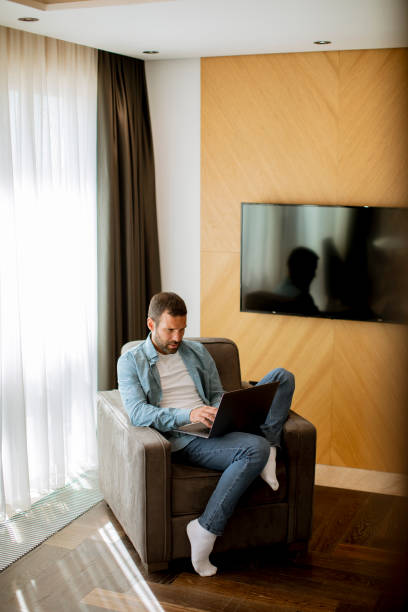 istock Young man using laptop in the living room 1392317509