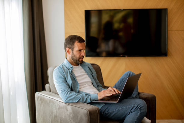 istock Young man using laptop in the living room 1392317513