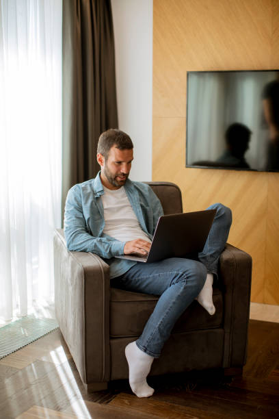 istock Young man using laptop in the living room 1392317520