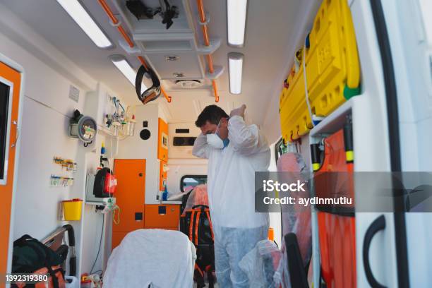 Male Emergency Paramedic With Hazmat Suit By Male Patient On Stretcher In Ambulance During Pandemic Stock Photo - Download Image Now