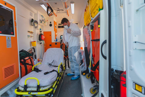 Male emergency paramedic with hazmat suit by male patient on stretcher in ambulance during pandemic stock photo
