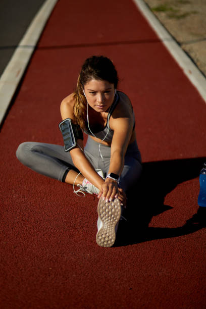 istock Young sporty woman doing stretching exercise on running track 1392320515