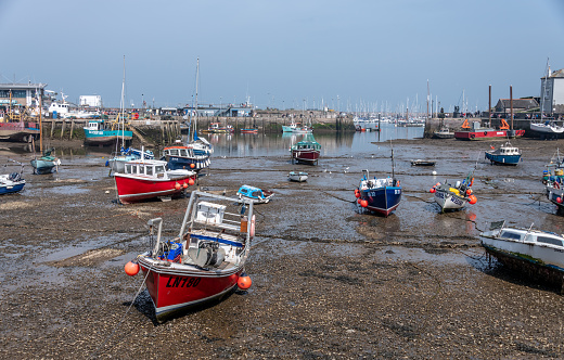 Brixham, UK. Saturday 16 April 2022. Low tide with boats moored in Brixham Harbour