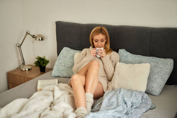 istock Young woman enjoying a good book at home in bed while drinking coffee 1392320943