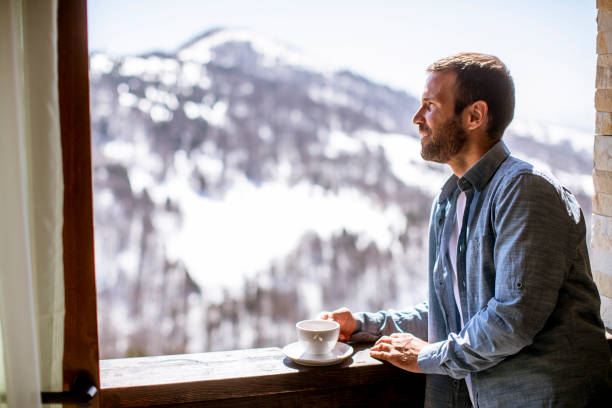 istock Young man with cup of hot tea at winter window 1392321020