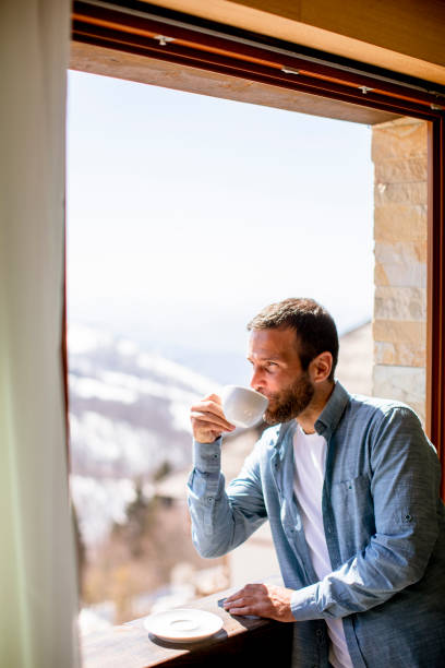 istock Young man with cup of hot tea at winter window 1392321021