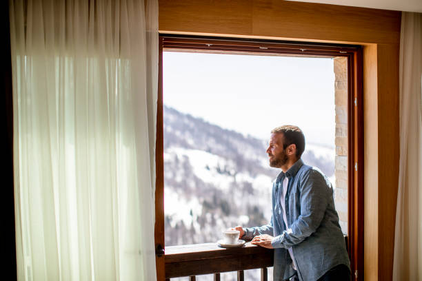 istock Young man with cup of hot tea at winter window 1392321042