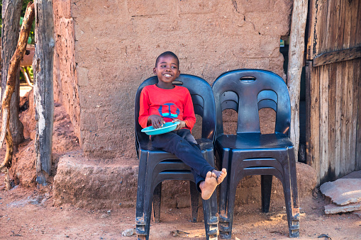 Small African boy in the village eating a traditional meal