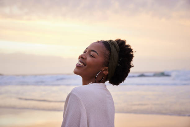 istock Laughing young woman standing on a sandy beach at sunset 1392324410