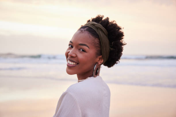 istock Smiling young woman looking over her shoulder on a beach at sunset 1392324946