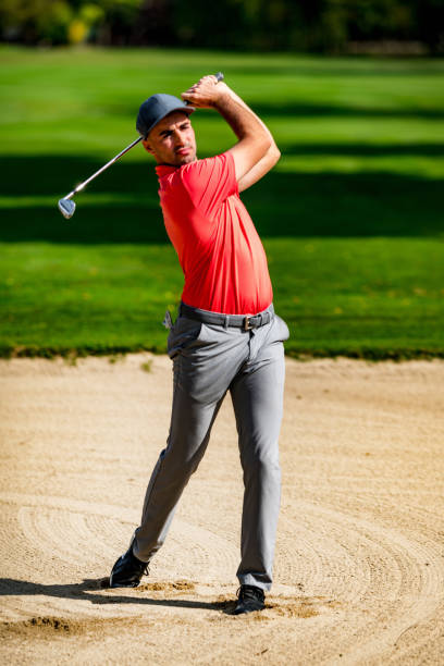 A B&W image of a golfer hitting out of a sand trap.