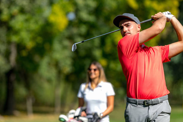 coppia di golfisti in un tee box, godendosi una partita a golf in una bella giornata di sole, uomo che colpisce una palla - golf playing teeing off men foto e immagini stock