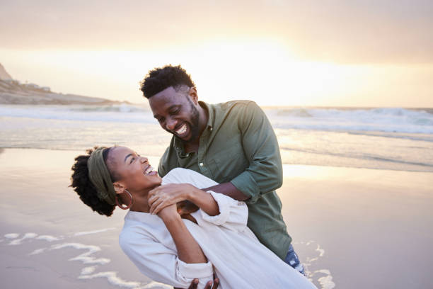 istock Laughing young couple having fun at the beach at sunset 1392326551