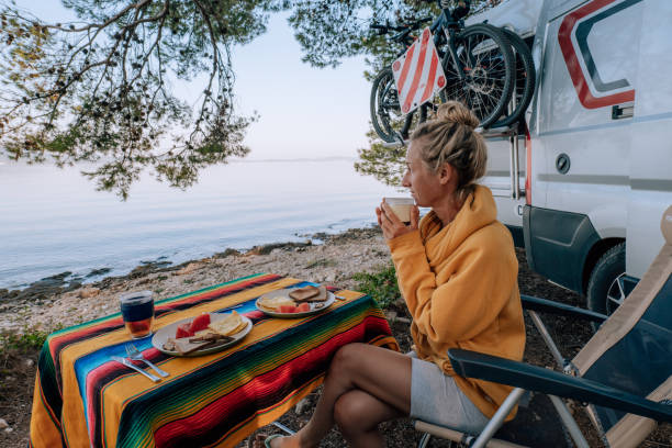 Woman enjoys breakfast near her van, beach view