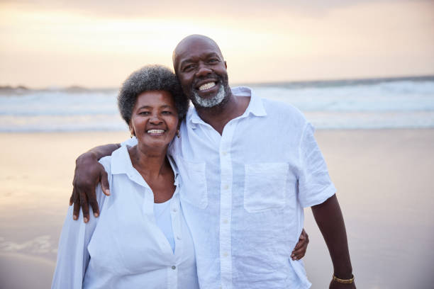 istock Smiling senior couple standing on a beach at sunset 1392327951