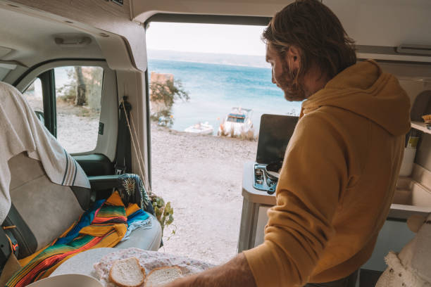 istock Man cooking in a camper-van, ocean view 1392328227
