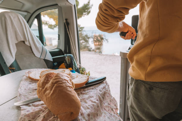 istock Man cooking in a camper-van, ocean view 1392328606